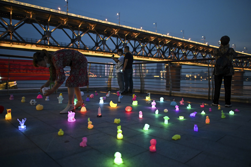 A woman sets out light-up toys along the Yangtze River in Wuhan, Hubei province, Sept. 24, 2020. Hector Retamal via People Visual