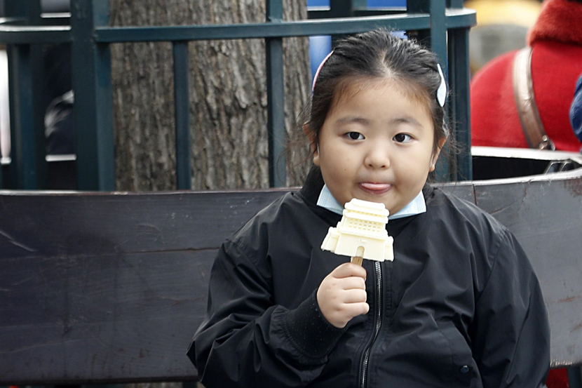 A girl enjoys a popsicle in Beijing, Oct. 8, 2020. Han Haidan/CNS/People Visual