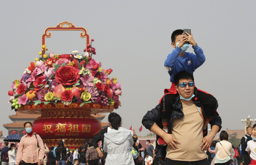 A boy takes photos from his father’s shoulders in Tiananmen Square, Beijing, Oct. 7, 2020. IC