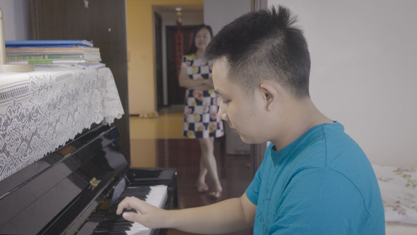 Cai Lechen plays piano at home, while his mother Mei Li watches, in Shanghai, September 2020. Zhu Jiaqi for Sixth Tone