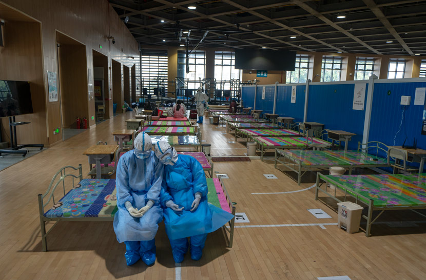 Two medical workers take a break at a “fangcang” shelter hospital in Wuhan, Hubei province, March 10, 2020. Fei Maohua/Xinhua