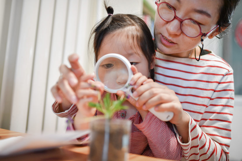 A mother teaches her daughter how to observe plants at home in Beijing, March 17, 2019. Mai Tian/People Visual