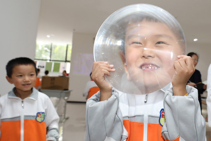 A pupil holds a magnifying lens at a primary school in Xi’an, Shaanxi province, Oct. 20, 2020. IC