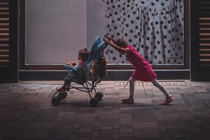 A girl pushes a toddler in a stroller, in Beijing, 2018. Zhang Chi/People Visual
