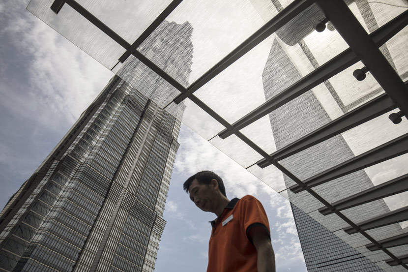 A man walks past the Jin Mao Tower (left) and the Shanghai World Financial Center, Shanghai, 2018. Qilai Shen/Bloomberg via People Visual