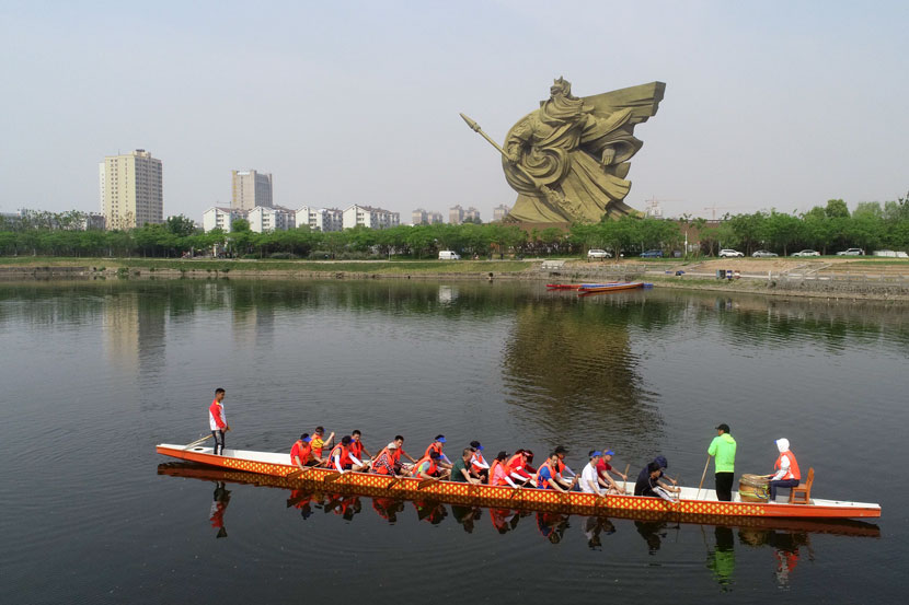 A team of rowers passes in front of a statue of Guan Yu in Jingzhou, Hubei province, May 3, 2019. Li Fuhua/People Visual