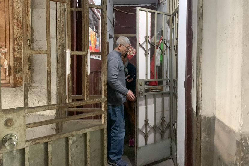Lü Caiqiang opens the door to enter his 18-square-meter apartment in Pengpu New Village, Shanghai, Nov. 4, 2020. Wang Lianzhang/Sixth Tone