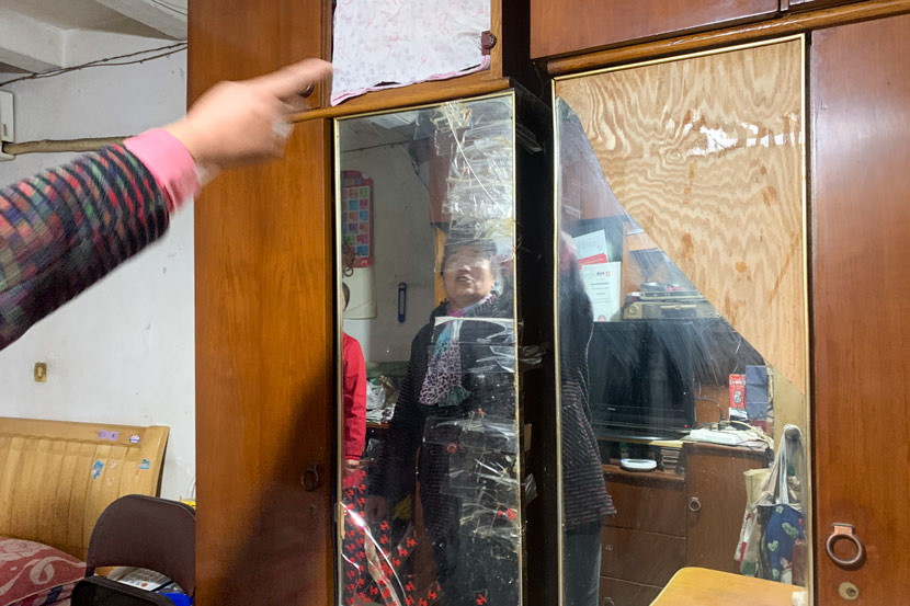Wang Liyuan points to her closet’s broken mirror in Pengpu New Village, Shanghai, Nov. 4, 2020. She dreams of a new one in her next apartment. Wang Lianzhang/Sixth Tone
