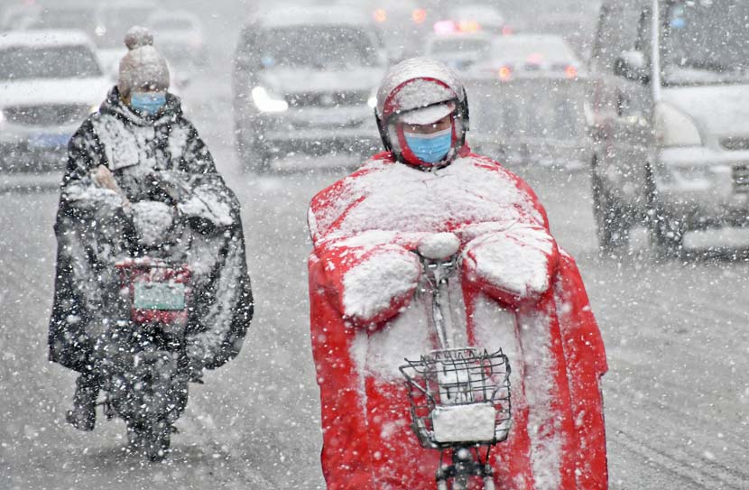 People ride electric scooters through snowfall, Yantai, Shandong province, Nov. 28, 2020. People Visual