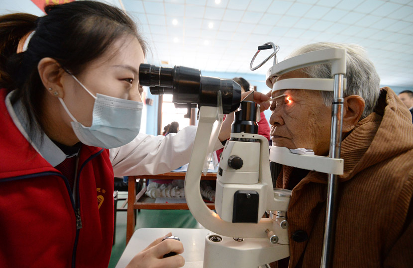 A medical volunteer performs an eye exam for an elderly woman at a residential community in Handan, Hebei province, Dec. 4, 2020. Hao Qunying/People Visual