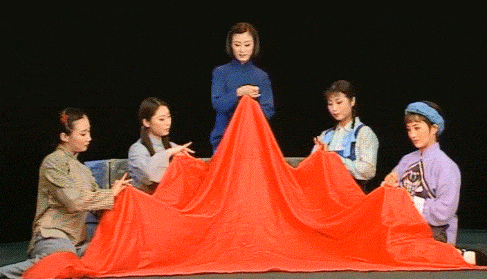 A GIF shows Jiang Zhujun sewing a red flag with her fellow inmates, from Zhang Huoding’s Peking Opera adaption. From @huhan1988 on Bilibili