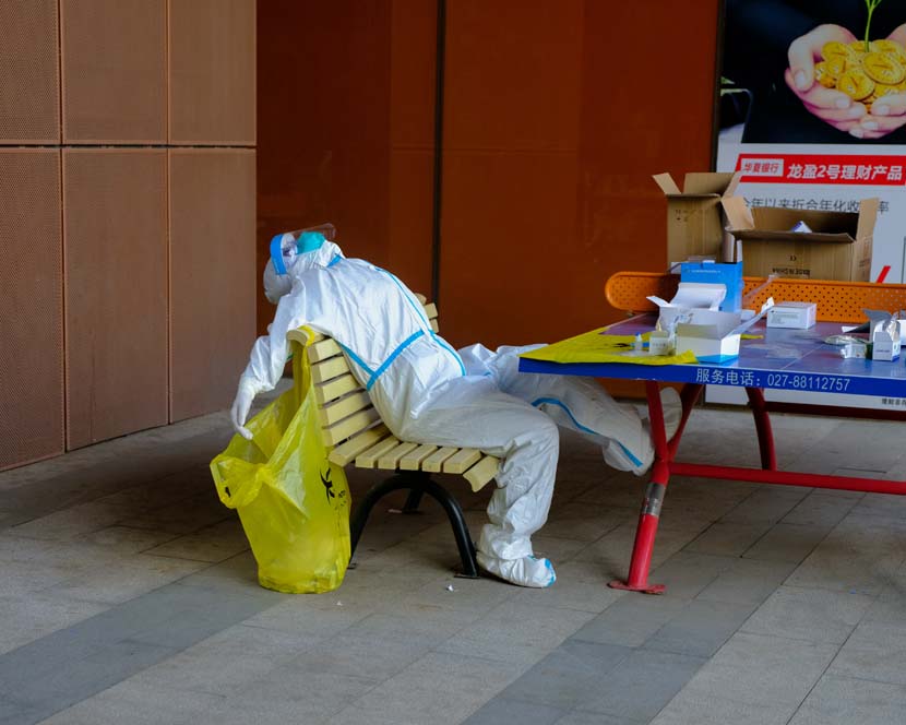 An exhausted medical worker takes a break after giving nucleic acid tests to hundreds of people returning back to work at Wuhan Optical Valley, Hubei province, April 13, 2020. Shi Yangkun/Sixth Tone