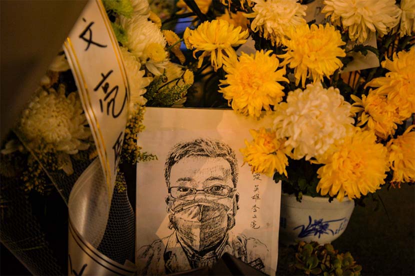 A portrait of Li Wenliang is placed among flowers sent by residents paying their respects to the doctor at the West Lake section of Wuhan Central Hospital, Hubei province, Feb. 7, 2020. Li Wenliang, an ophthalmologist believed to be one of eight people reprimanded by police in early January for “spreading rumors” about a new SARS-like virus, died early Friday morning at the age of 34. Shi Yi for Sixth Tone