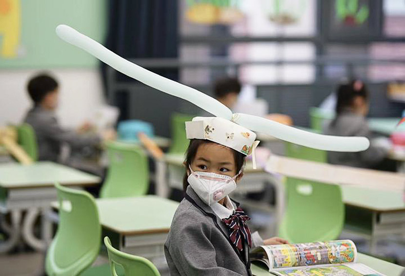 A girl wears a social-distancing “one-meter-hat” during the first day back at a primary school in Hangzhou, Zhejiang province, April 2020. Zhejiang Daily