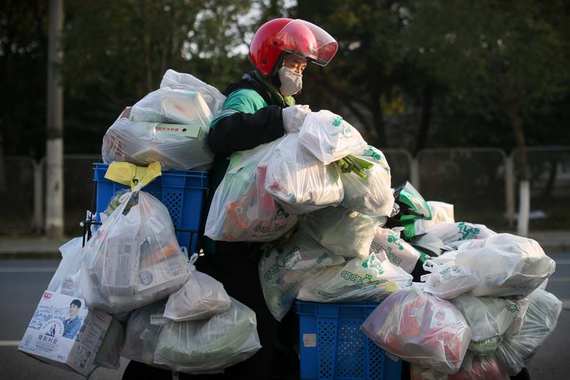 A delivery man carries daily necessities and fresh food in Shanghai, Feb. 9, 2020. Residents rely on delivery companies to send groceries, so they don’t have to shop in crowded supermarkets during the novel coronavirus outbreak period. Zhu Weihui for Sixth Tone