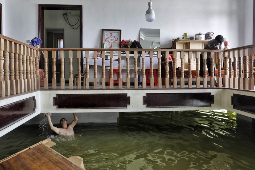 A villager cleans the ceiling of a flooded ground floor in Youdunjie Town, Jiangxi province, July 7, 2020. Li Zhanjun/Southern Metropolis Daily