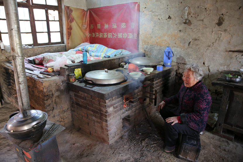 An elderly woman sits by her home's hearth and bed-stoves  in Jiaodai Town, Shaanxi province, April 2019. Wei Yongxian/IC