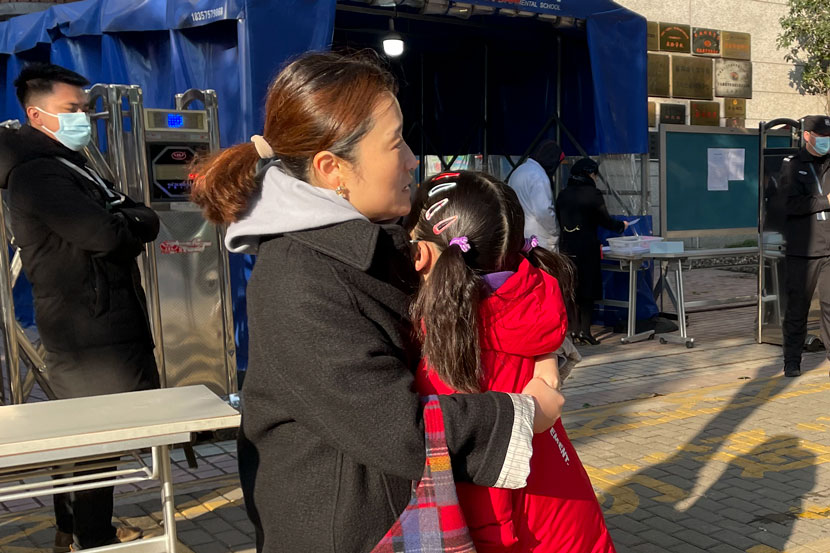 A mother comforts her daughter while waiting for her father to deliver the ID card she needs to get into the test center in Shanghai, Dec. 19, 2020. Zhang Shiyu for Sixth Tone