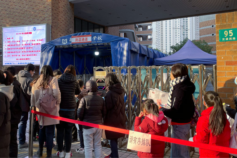 Children line up to get their temperatures tested before entering the test center in Shanghai, Dec. 19, 2020. Zhang Shiyu for Sixth Tone