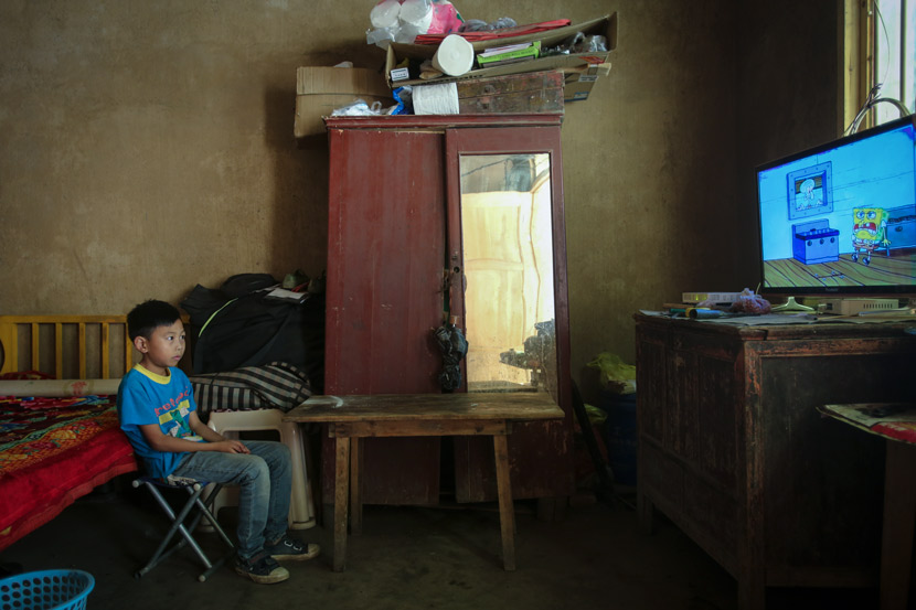 A boy watches TV alone at home, in Bijie, Guizhou province, Aug. 2, 2018. Luo Binhao/People Visual