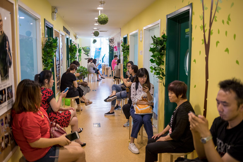 Parents wait for their children in a hallway while they attend extracurricular courses in Beijing, 2018. Li Jianguo/People Visual