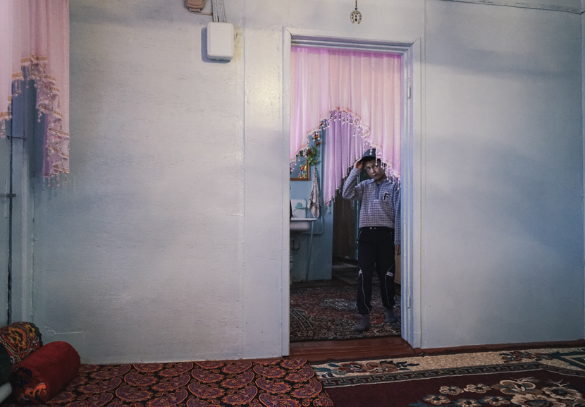 A boy peers through a doorway in his home in northern Uzbekistan, Oct. 9, 2017. Courtesy of Liu Zichao