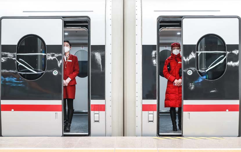 Attendants wait for passengers to board a train at Beijing Railway Station, Jan. 28, 2021. People Visual