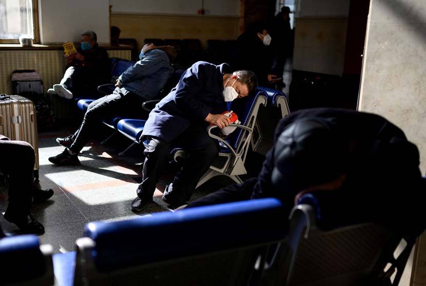 People rest while waiting for their trains at Beijing Railway Station, Jan. 28, 2021. AFP/People Visual