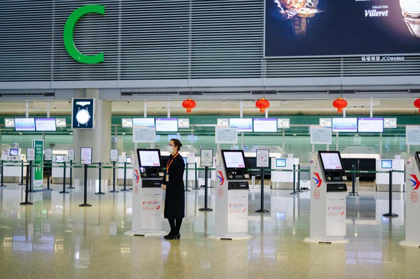 A China Eastern Airlines staff member waits to assist checking-in passengers at Shanghai Hongqiao International Airport, Jan. 28, 2021. Wu Huiyuan/Sixth Tone