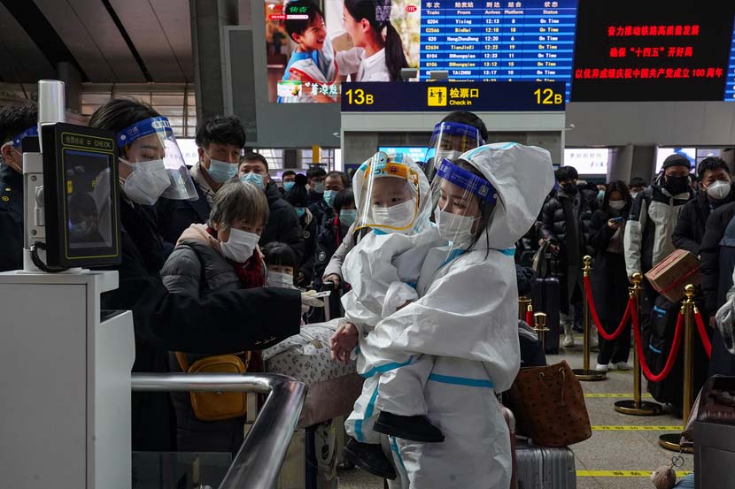A mother and child in full hazmat suits pass through an automatic ticketing gate at Beijing South Railway Station, Jan. 28, 2021. Wang Jiaxing/China Youth Daily