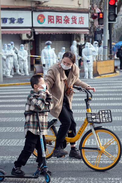 A mother and son walk past a blocked-off neighborhood in Shanghai, Jan. 27, 2021. Lü Wei/People Visual