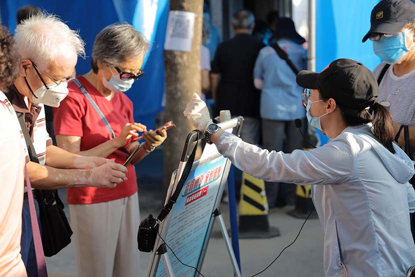 Elderly people scan a QR code to book a reservation to visit a public park in Beijing, July 6, 2020. People Visual