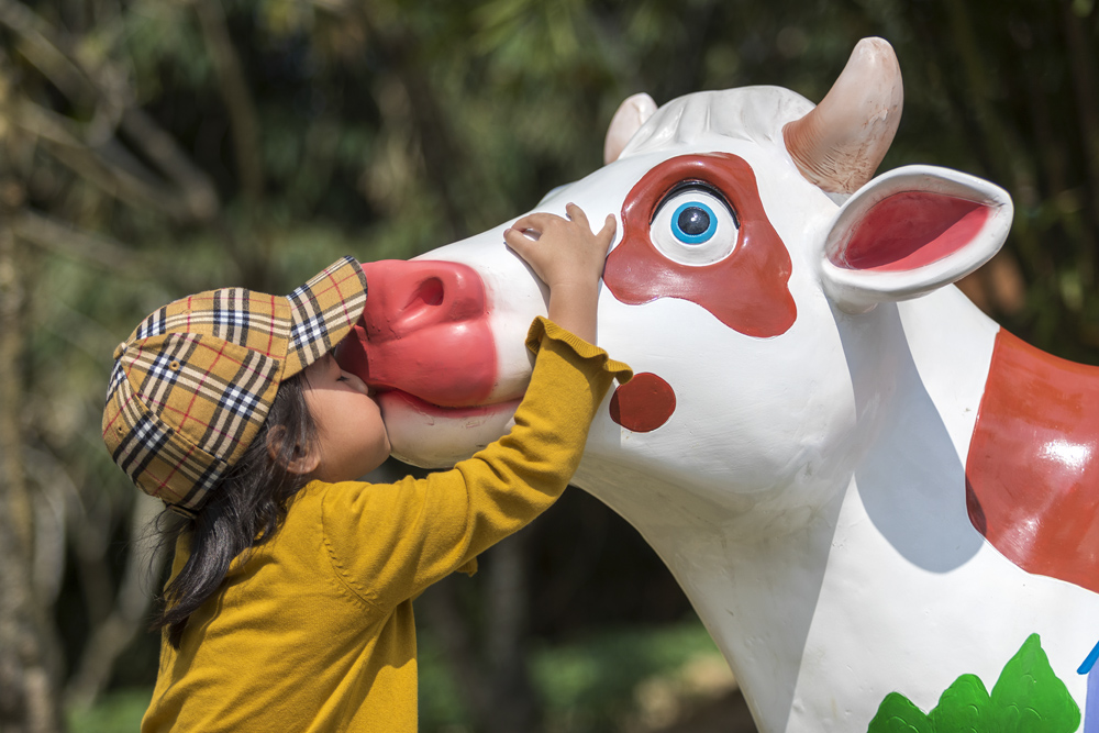 A girl kisses a cow statue in Tunchang County, Hainan province, Feb. 16, 2021. Li Taotao/People Visual