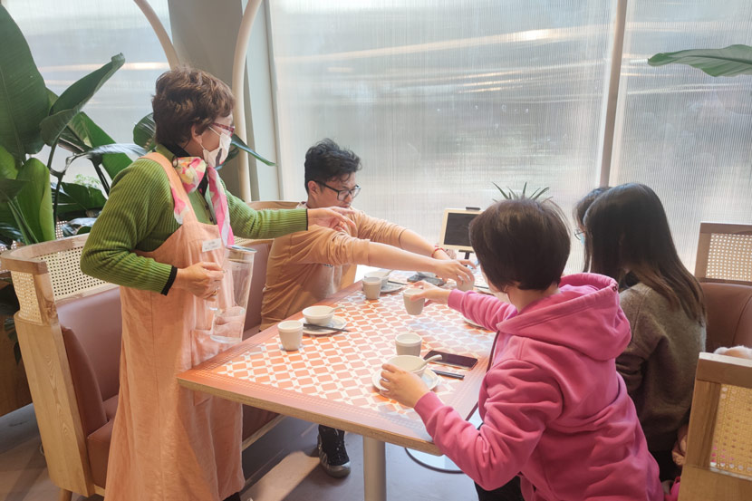 An elderly staff member serves tea at the Forget-Me-Not Café in Shanghai, Feb. 24, 2021. Zhang Chaoyan for Sixth Tone