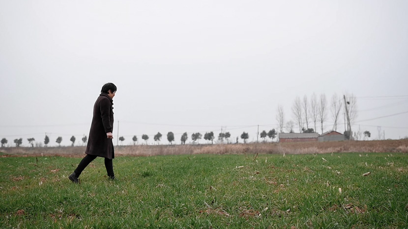 Han Shimei walks through a field in Xichuan County, Henan province, February 2021. Zeng Yinzi for Sixth Tone