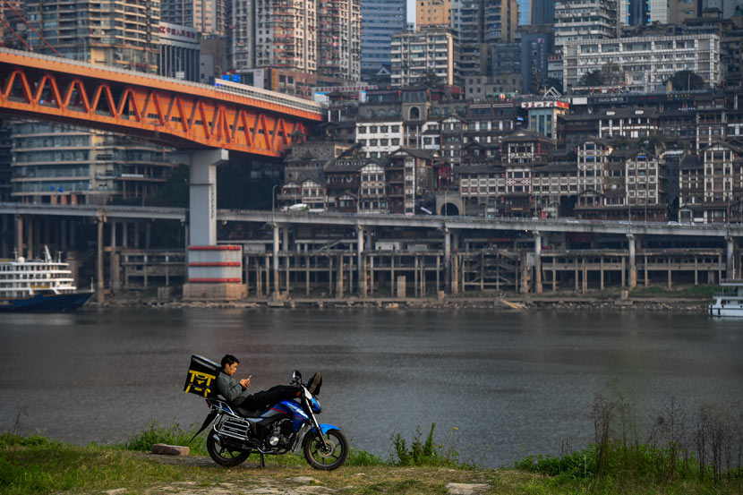 A delivery driver takes a break by the Jialing River in Chongqing, March 2020. Li Xiangbo/People Visual