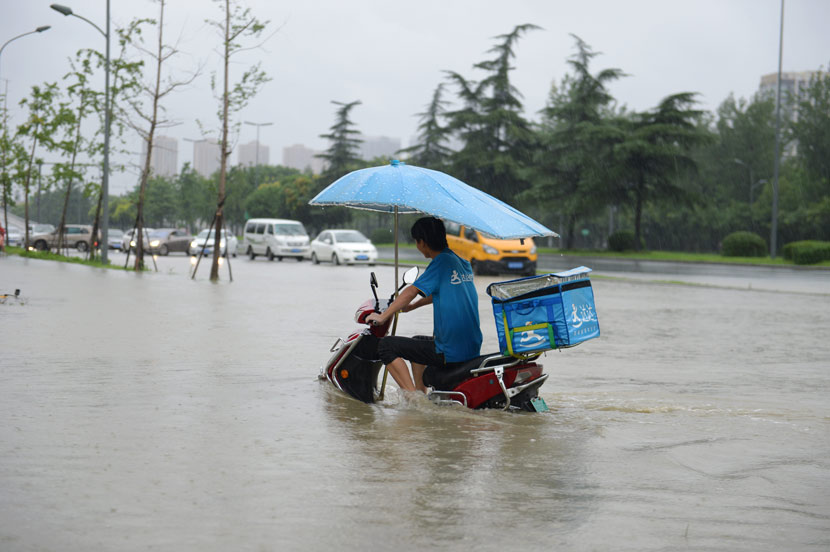 A delivery driver crosses a flooded street in Chengdu, Sichuan province, Aug. 11, 2020. Gao Han/People Visual