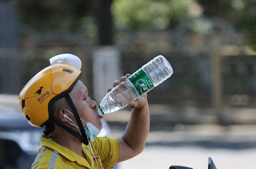 A delivery worker drinks water on a hot summer day in Beijing, July 2020. Yang Kejia/CNS/People Visual