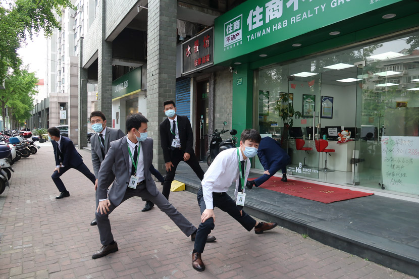 Real estate agents perform exercises outside an office in Shanghai, April 2020. Wang Rongjiang/People Visual