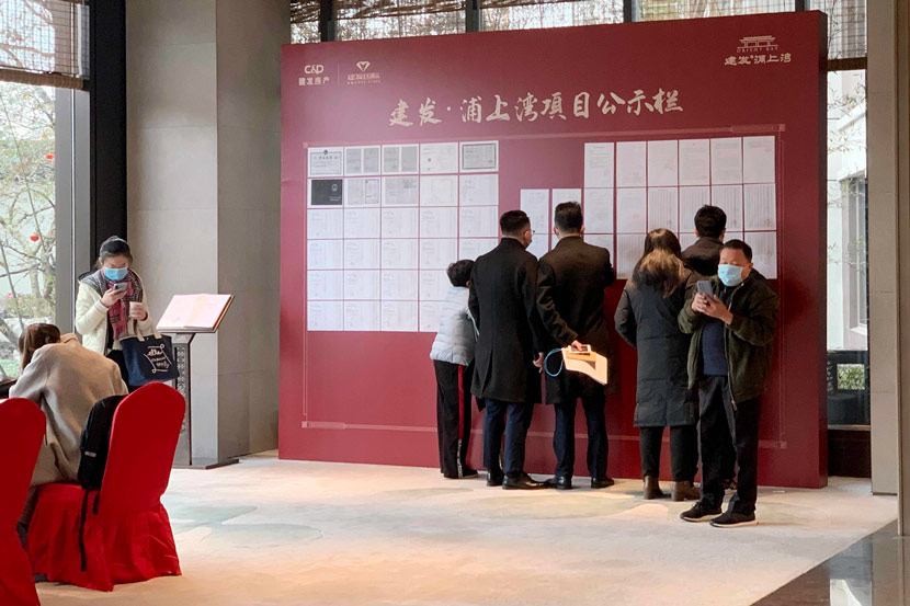 Consumers read bulletins posted in the sales office of a new real estate development in Shanghai, Feb. 6, 2021. Bai Kelin/IC