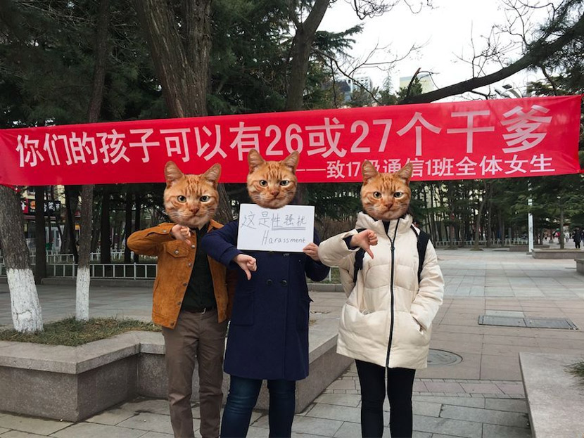 Three students pose in front of a Girls’ Day banner that reads, “Your daughter has 26 or 27 godfathers (among her male classmates).” Courtesy of Joanne