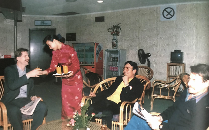 A ground service staff member serves drinks to passengers in a VIP room at Shanghai Hongqiao Airport, 1993. Courtesy of Luo Keping