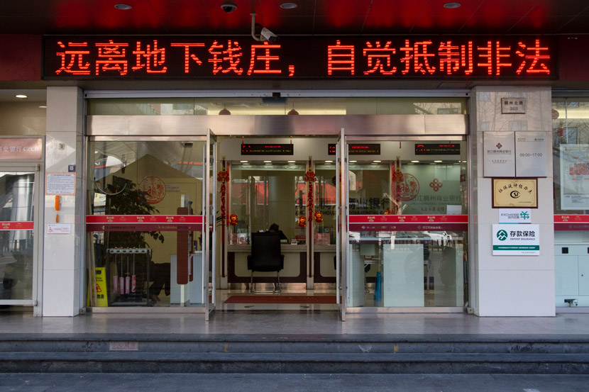 The exterior view of a bank in Yiwu, Zhejiang province, March 14, 2021. The banner above the door reads: “Stay away from underground banks, resist illegal foreign exchange.” Wu Peiyue/Sixth Tone