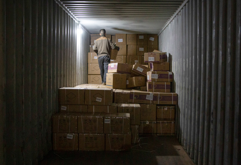 A worker stacks packages at a warehouse in Yiwu, Zhejiang province, March 14, 2021. Wu Peiyue/Sixth Tone