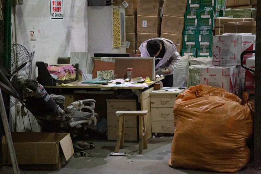 A worker checks shipping records at a warehouse in Yiwu, Zhejiang province, March 14, 2021. Wu Peiyue/Sixth Tone