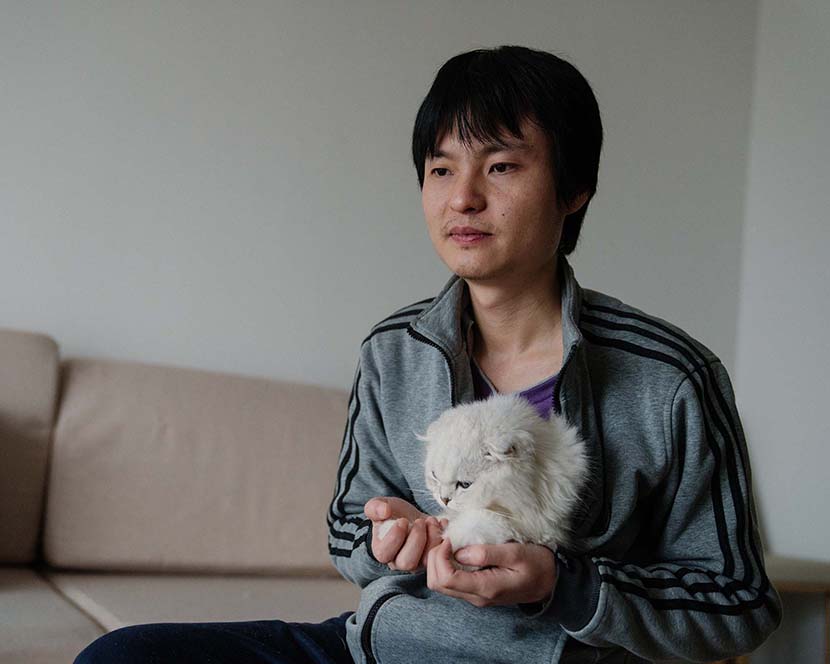 Sun Wenlin poses for a photo with the couple’s pet cat at their home in Changsha, Hunan province, March 16, 2021. Wu Huiyuan/Sixth Tone