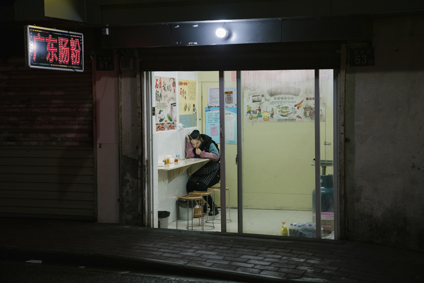 A waiter sits in the corner of a restaurant in Wuhan, Hubei province, April 2, 2021. Shi Yangkun/Sixth Tone