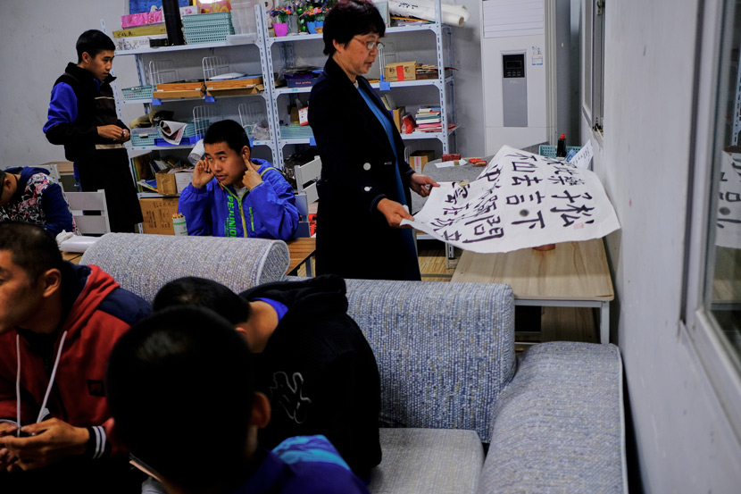 All of the residents and carers at Home of the Stars gather in a downstairs classroom to take part in evening activities, in Jinzhai County, Anhui province, March 2021. Yu (right) helps her son practice calligraphy. Wu Huiyuan/Sixth Tone