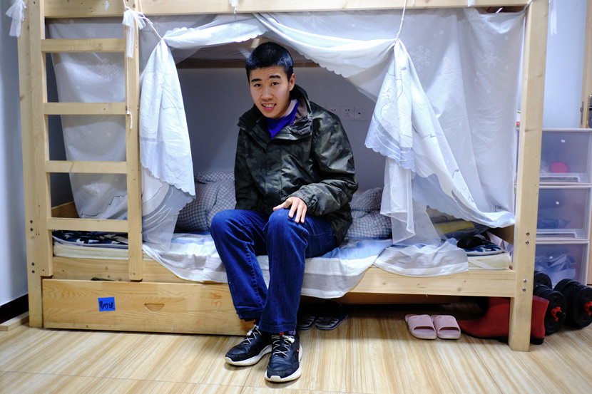 Yu Hua’s son Yi Xingjian, 25, sits on his bed at Home of the Stars in Jinzhai County, Anhui province, March 2021. Wu Huiyuan/Sixth Tone