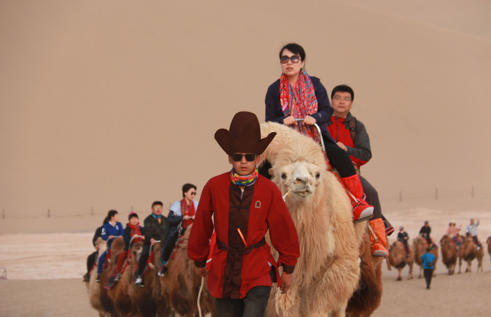 Tourists ride camels in Dunhuang, Gansu province, May 1, 2021. Zhang Xiaoliang/People Visual